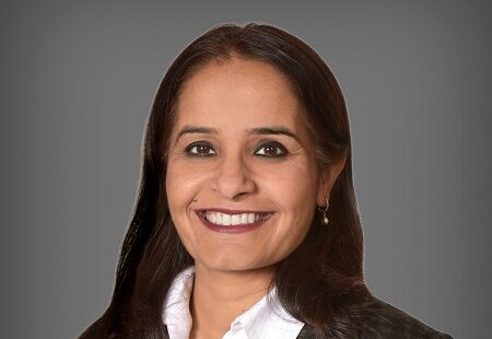 a woman with long brown hair smiling. She is wearing a business suit
