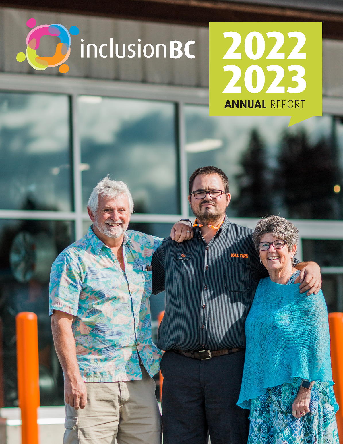 Three people standing in front of a tire shop. The person in the middle is a young man with short dark brown hair. He is wearing a striped button up shirt with the text Kal Tire written on one side of his chest and Tye on the other. To the right is an older man with short white hair and a white short trimmed beard. He is wearing a colourful short sleeve button up shirt with illustrations of fish printed on it and cargo shorts. To the right is an older lady with curly short brown hair. She is wearing purple rimmed glasses and a flowy blue dress with diamond shaped patterns. All three people have their arms over each other and are smiling while looking at the camera.